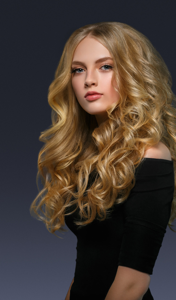 Молодая блондинка с красивыми длинными волосами в черном платье