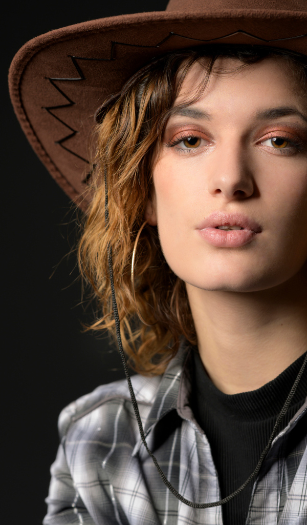 Young girl in a cowboy hat on a gray background
