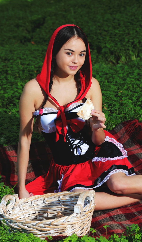 Молодая девушка в костюме сидит на траве, косплей