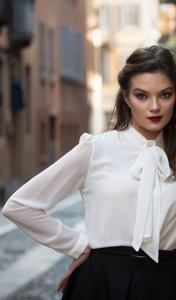 Молодая девушка в белой рубашке у стены