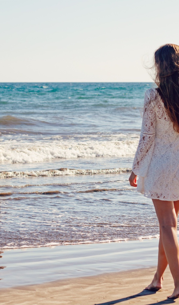 Молодая девушка в белом кружевном платье у моря