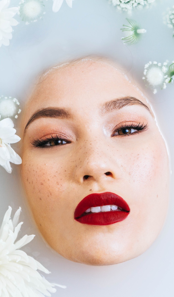 Молодая девушка лежит в ванной с цветами