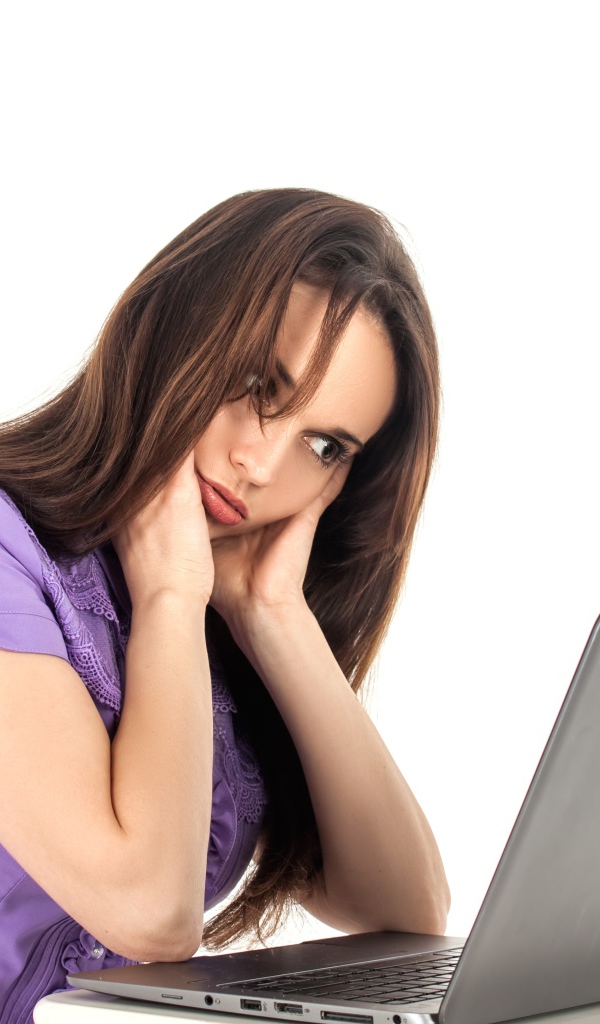 Молодая девушка сидит за ноутбуком на белом фоне