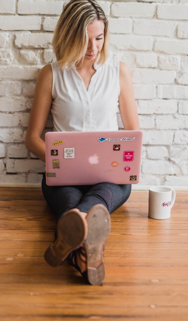 Молодая девушка студентка с ноутбуком и книгами у стены