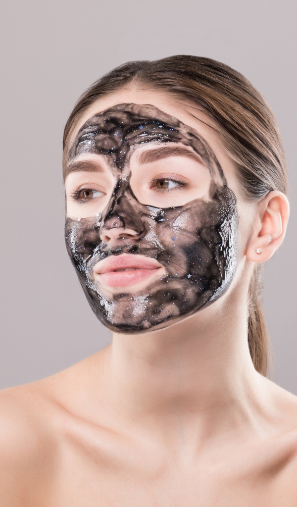 Молодая девушка с косметической черной маской на лице