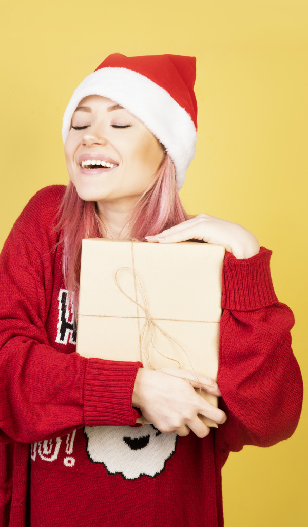 Улыбающаяся девушка в красном свитере с подарком на желтом фоне