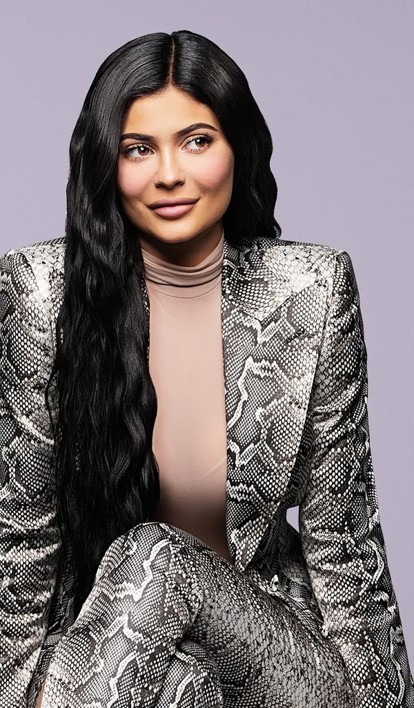 Длинноволосая модель Кайли Дженнер в костюме на сером фоне