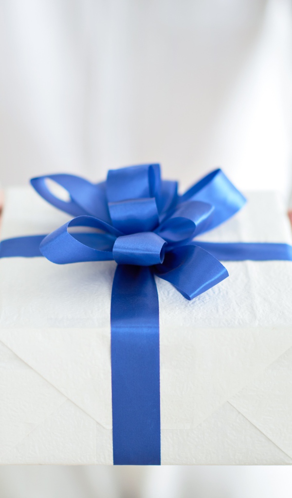 Подарок с голубым бантом в руках 