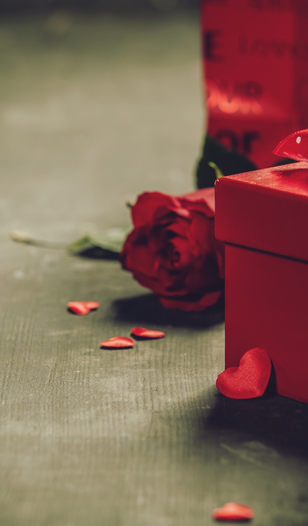 Red boxes with gifts on a table with a rose