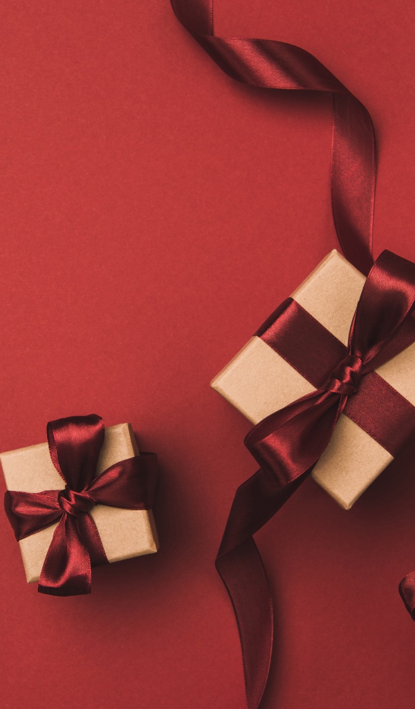 Три подарочные коробки с бантами на красном фоне
