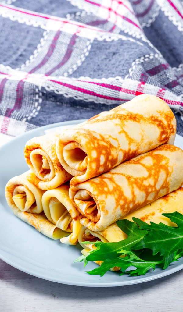 Блинчики на столе с помидорами и полотенцем угощение на Масленицу 2020