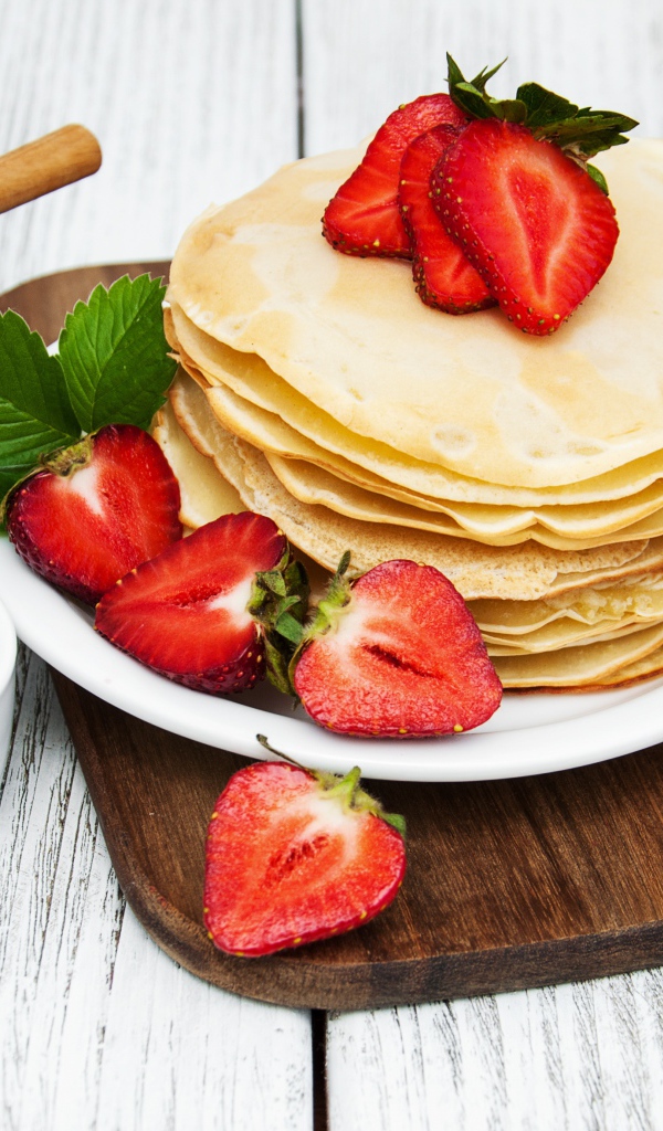 Блины с клубникой на столе с медом и джемом на праздник Масленица 2020