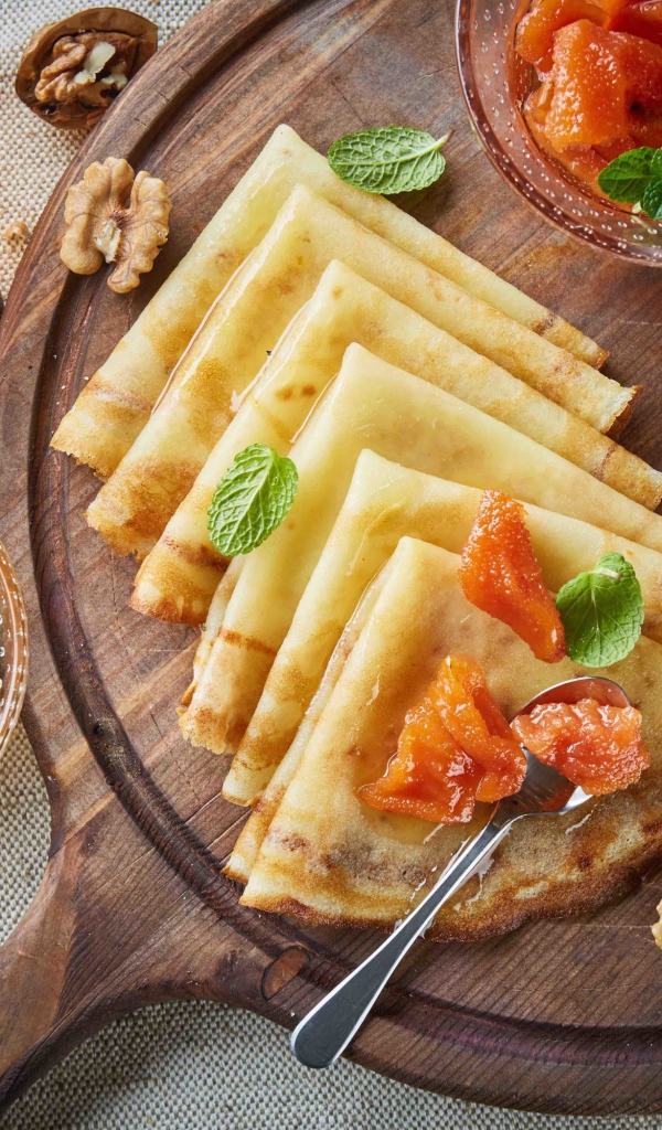 Тонкие блины с орехами и джемом на столе на Масленицу