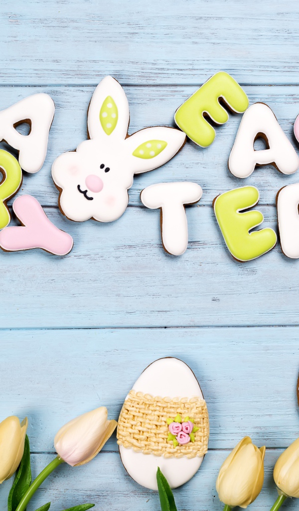 Красивое пасхальное печенье на столе с тюльпанами 