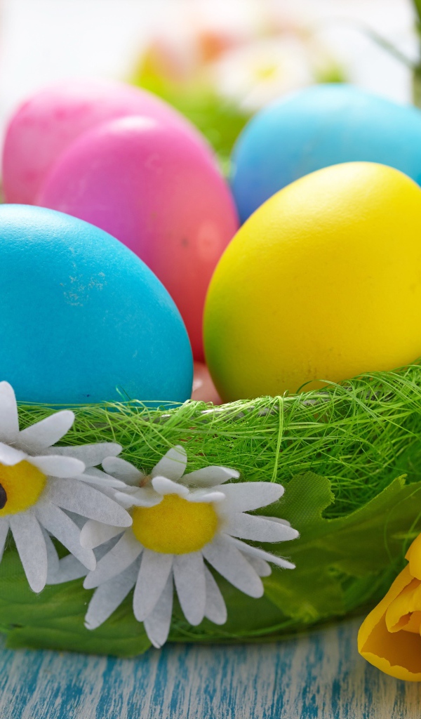 Разноцветные яйца на столе с тюльпанами на Пасху