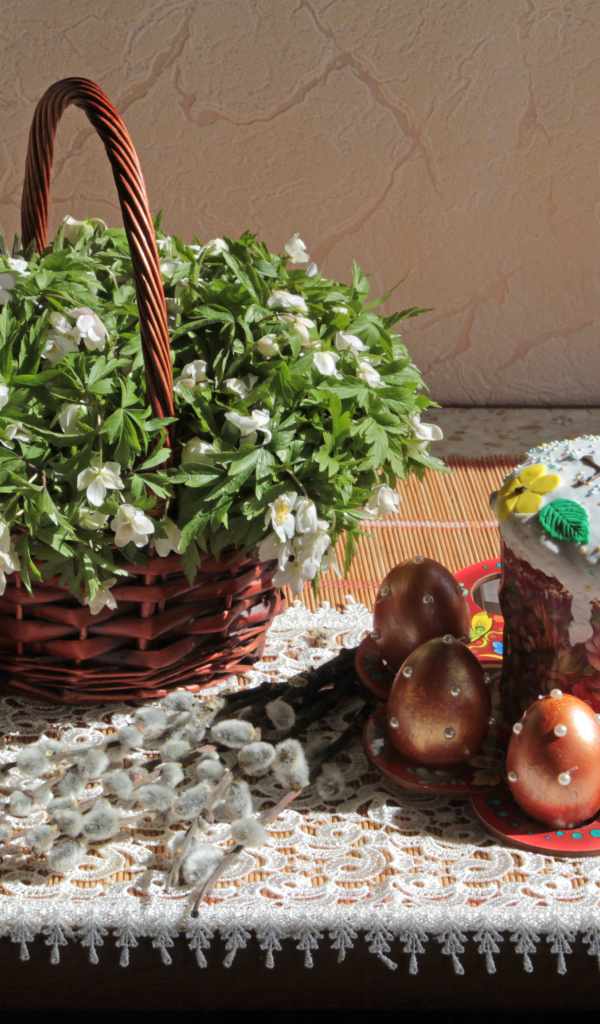 Пасхальный кулич с яйцами на столе с корзинкой цветов на праздник