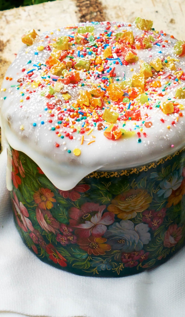 Кулич с глазурью на столе с цветами и яйцами на Пасху