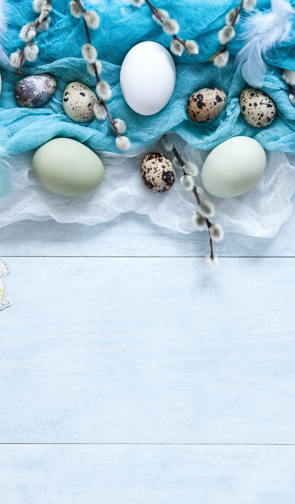 Яйца на ткани с ветками вербы на столе