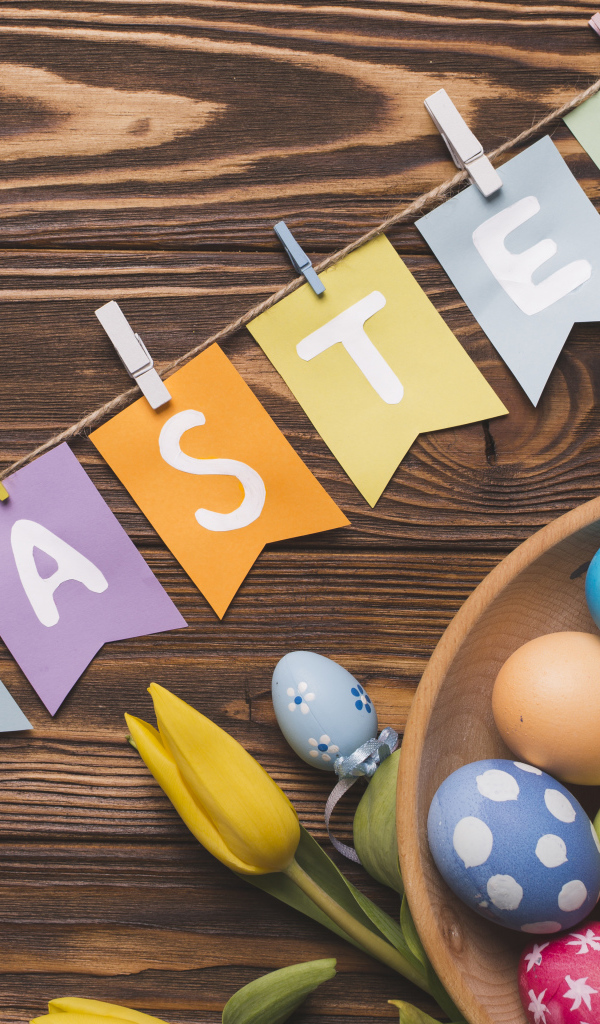 Надпись Пасха на столе с крашеными яйцами и тюльпанами