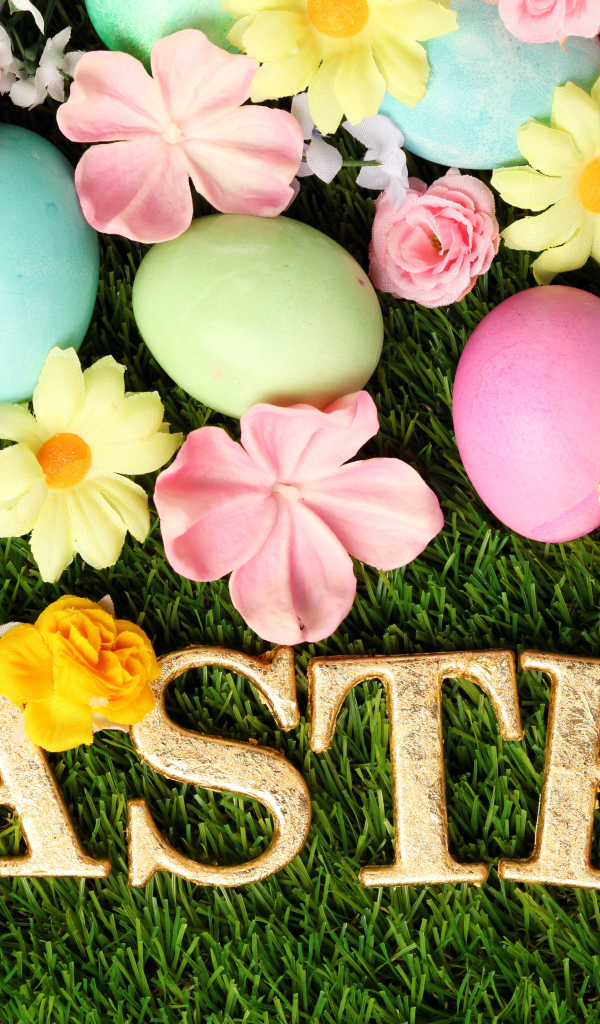 Надпись на траве с разноцветными яйцами и цветами на Пасху