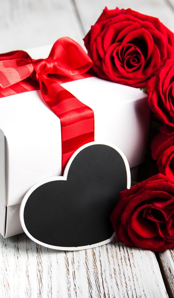Букет красивых красных роз на столе с подарком для любимой на 8 марта