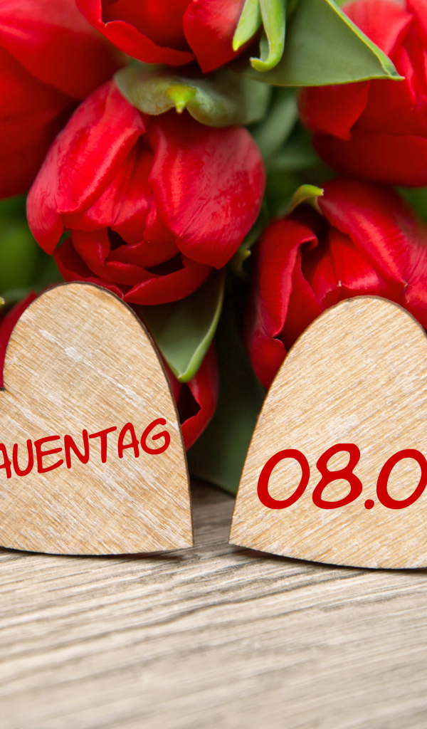 Два сердечка на столе с букетом красных тюльпанов на 8 марта 