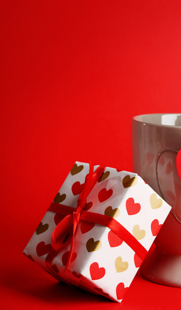Кружка, сердечко и подарок на красном фоне на День Святого Валентина 