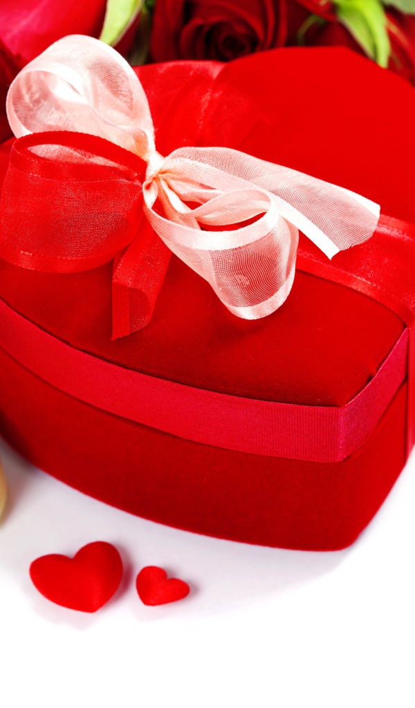 Красная коробка в форме сердца на столе с розами и конфетами для любимой