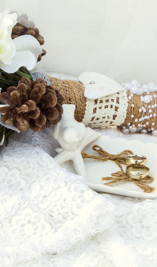 Букет невесты из цветом анемоны лежит на платье с обручальными кольцами