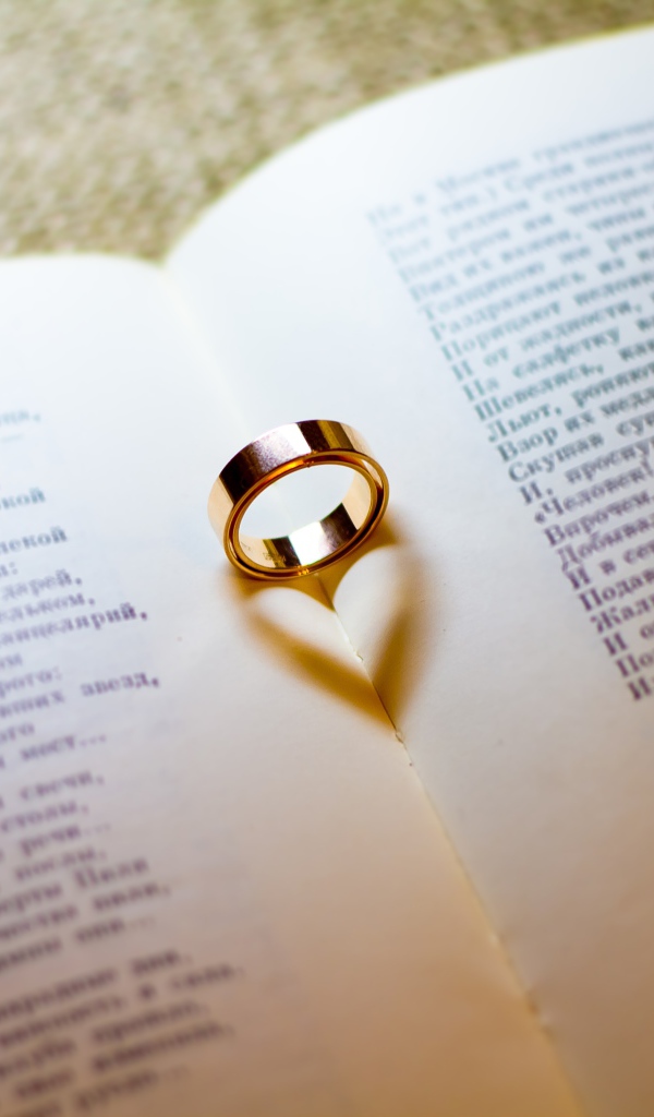Золотое обручальное кольцо лежит на открытой книге