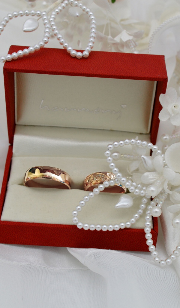 Золотые обручальные кольца в красной коробочке с украшениями