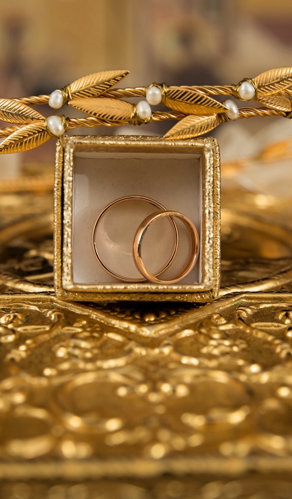 Два золотых обручальных кольца в коробке с венком 