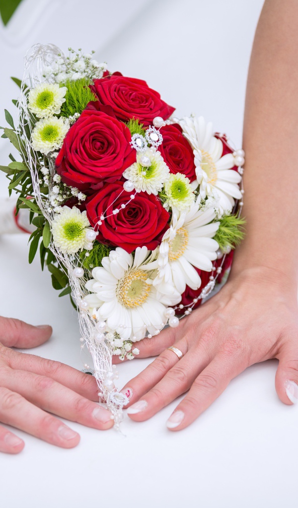Two hands with wedding rings and bridal bouquet