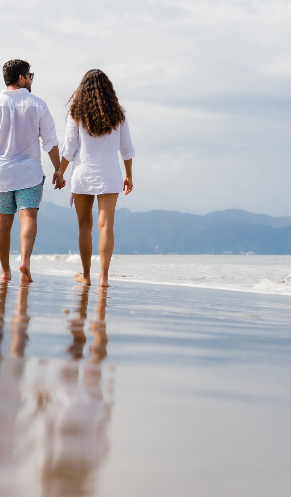 A couple in love walks on the wet sand by the sea