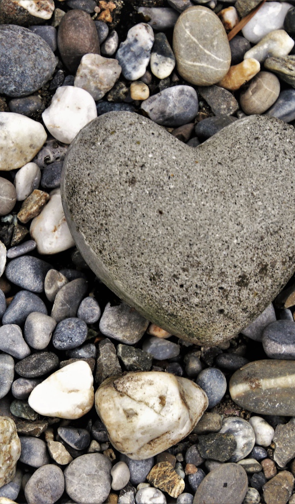 Большой камень в форме сердца лежит на морской гальке