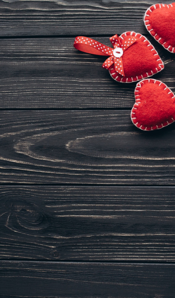 Много красных сердечек из фетра на деревянном столе