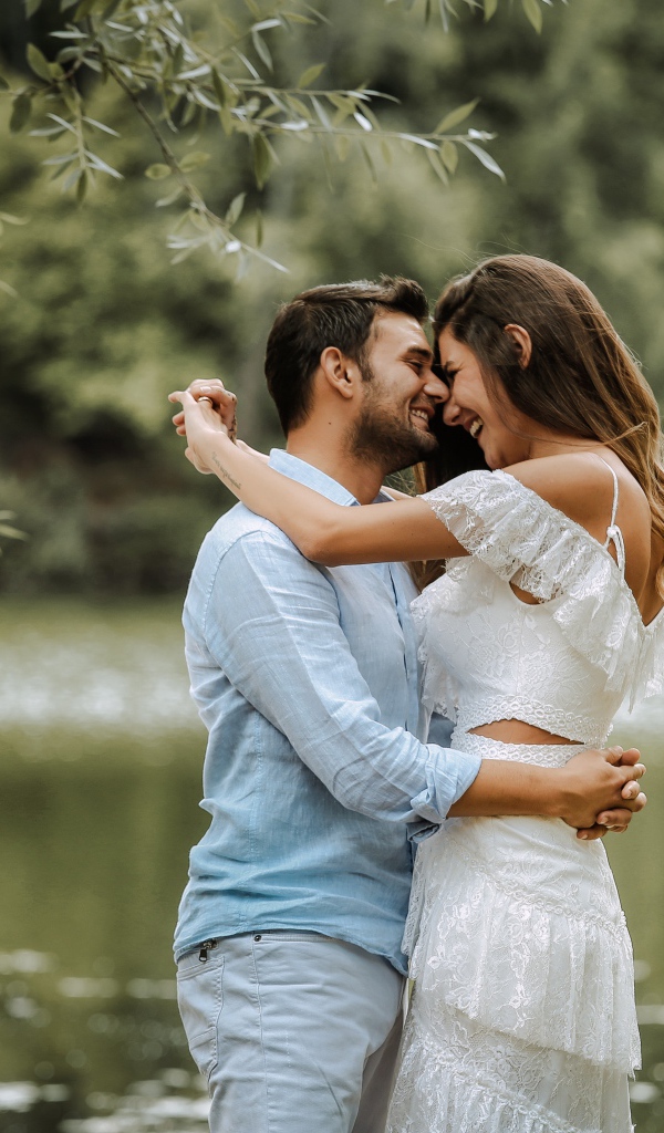 Влюбленная пара стоит у пруда в парке 