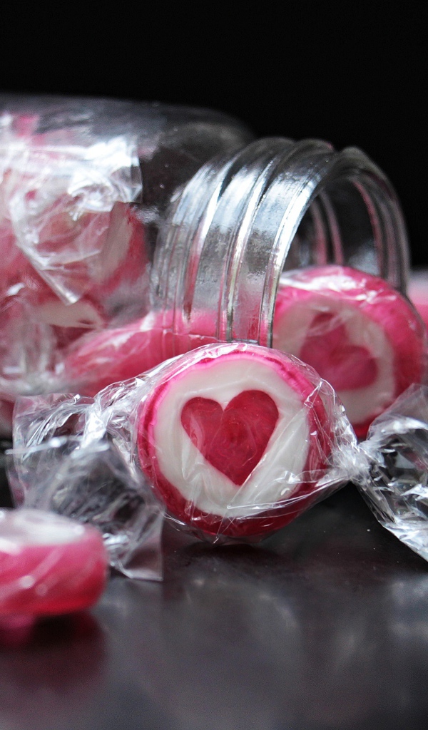 Конфеты с сердцем в стеклянной банке на черном фоне
