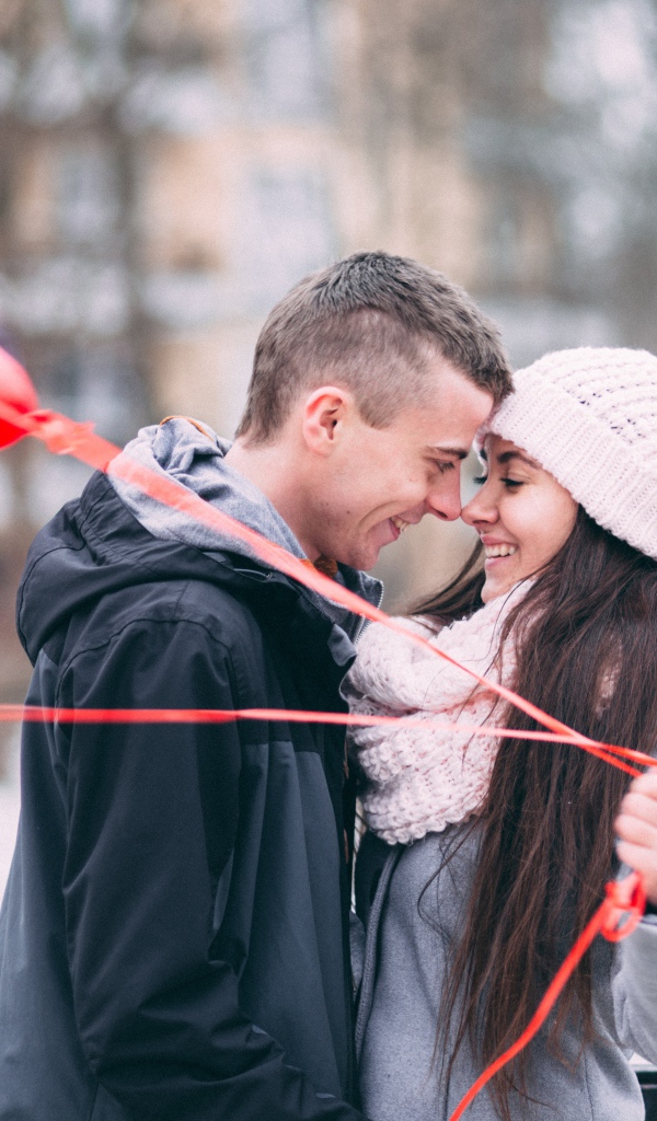 Влюбленная пара с воздушными шарами на улице зимой