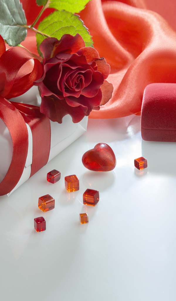 Подарки на белом столе с розой и красной тканью