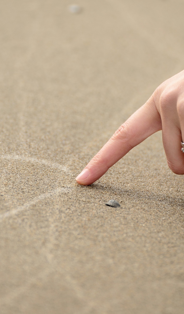 Девушка рисует сердце на песке 