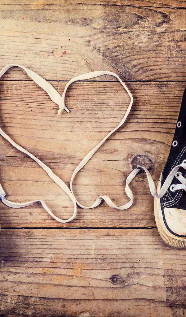 Сердце из шнурков кед на деревянном столе 