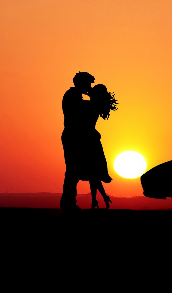 Целующаяся пара на фоне заката с автомобилем