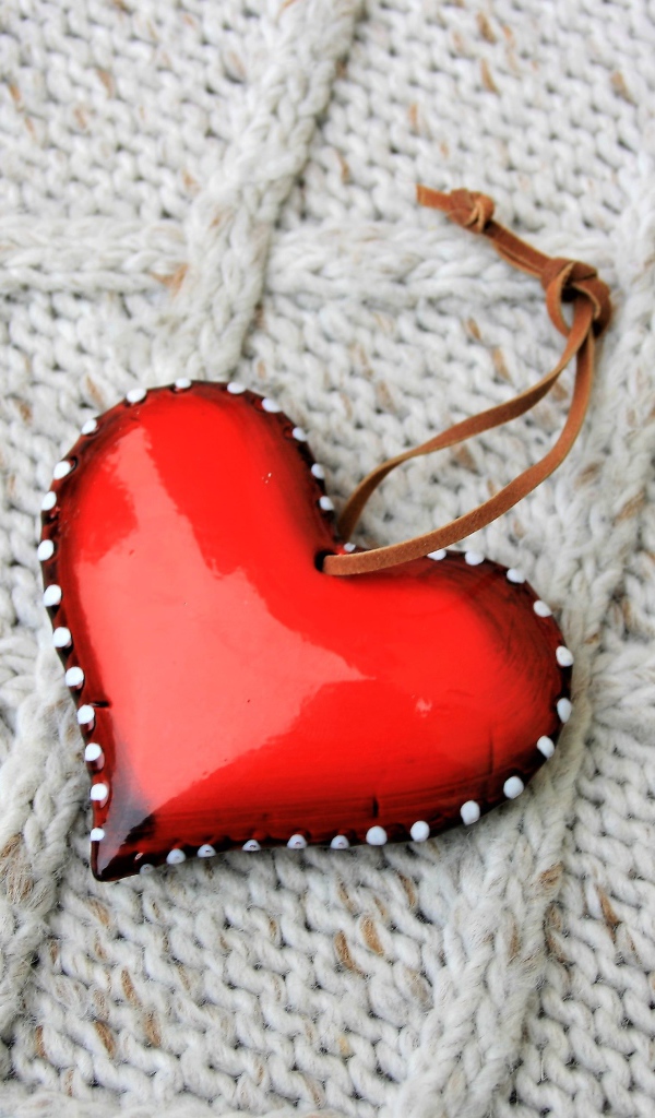 Красное сердце лежит на вязаном свитере 