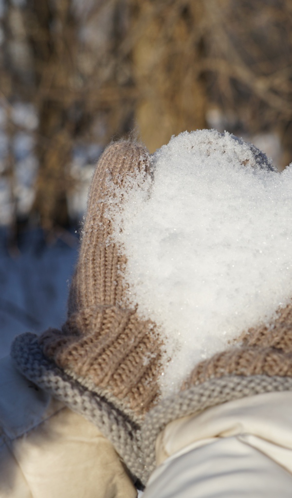 Снег в руках у девушки в перчатках 