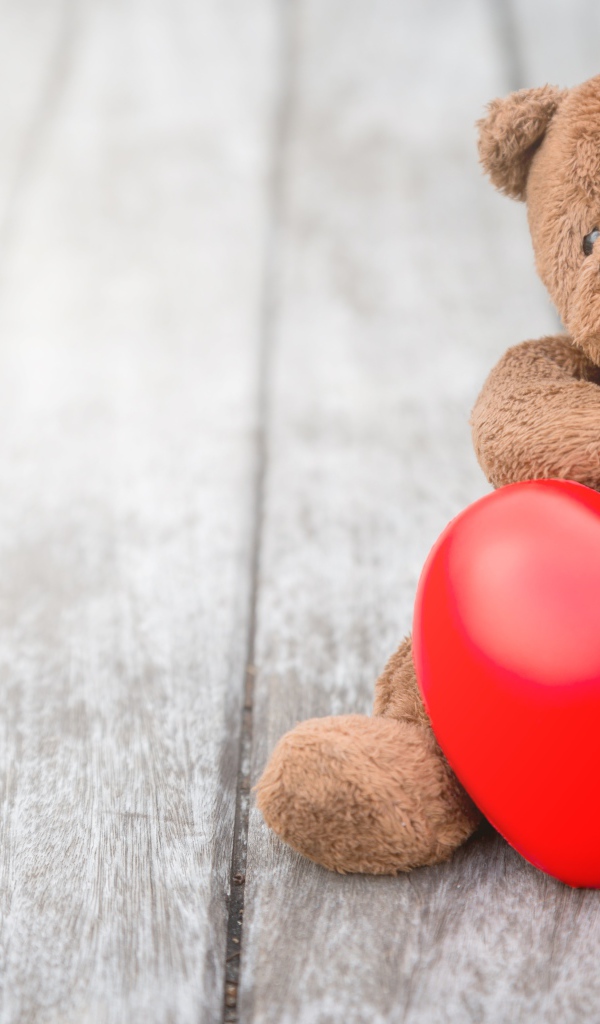 Медвежонок Тедди с красным сердцем сидит на столе