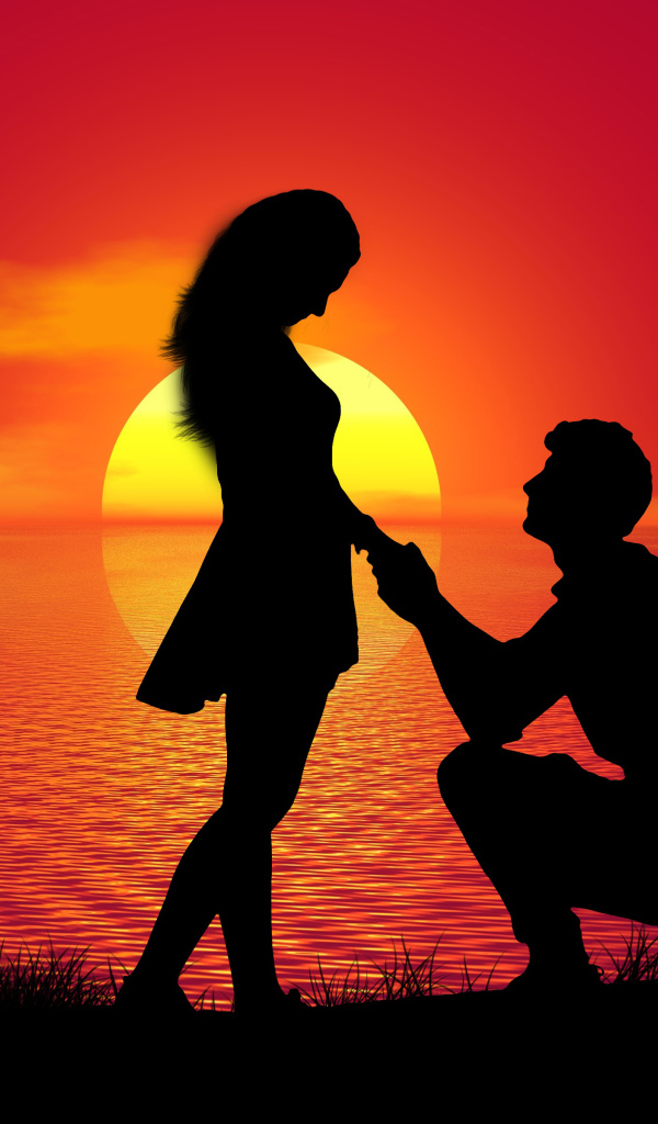 Парень делает девушке предложение на фоне заката у моря