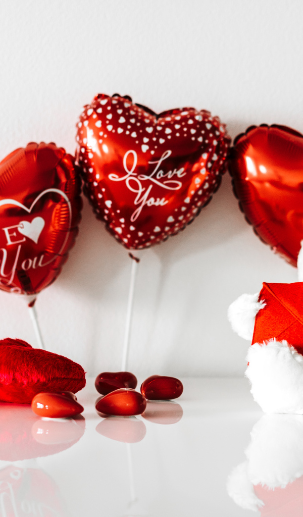 Белый мишка с подарками и шариками у стены