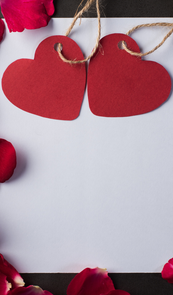 Белый лист бумаги с сердечками и лепестками роз 