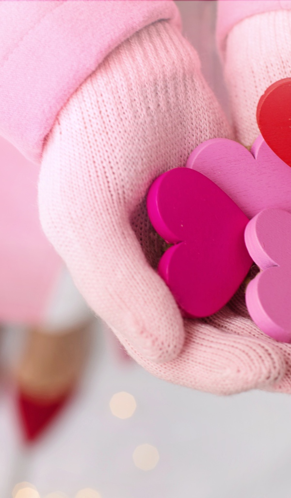 Деревянные сердечки в руках девушки в розовых перчатках 